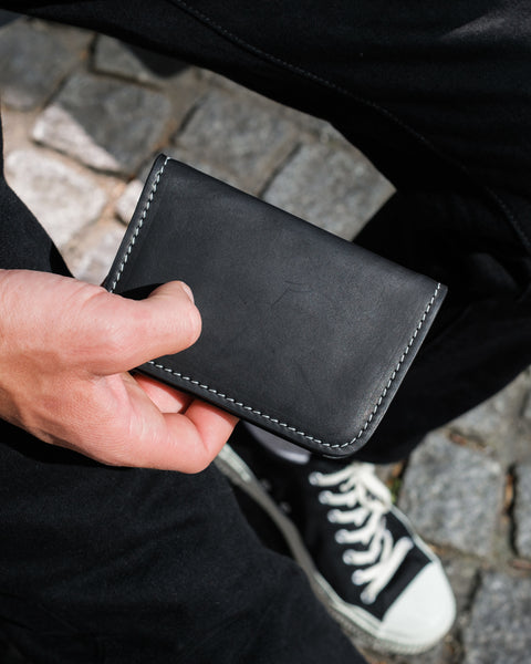 Person holding a black leather wallet with a blurred background