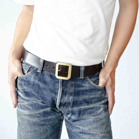 Model wearing OGL Single-Prong Garrison Leather Belt Full Brown solid brass buckle with faded raw denim, Durable Craftsmanship