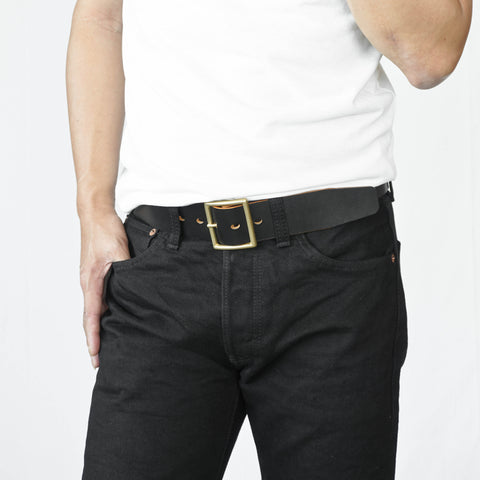 Model wearing OGL Vintage 1.75 Leather Belt Hand-Dyed Black handmade full-grain leather wide solid brass buckle in black raw denim