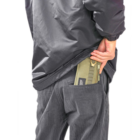 ORIGO Utility Wallet in olive abrasion-resistant technical canvas show by model tucking into back pocket by Obbi Good Label.